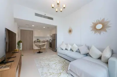 a living room with a blue couch and a kitchen at BNew Chic 1BR Apt Near Trump Golf w Pool and Gym in Dubai