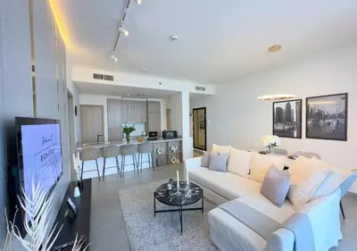 a living room with a white couch and a kitchen at Stunning 1BR in Stella Maris, City View, Marina in Dubai