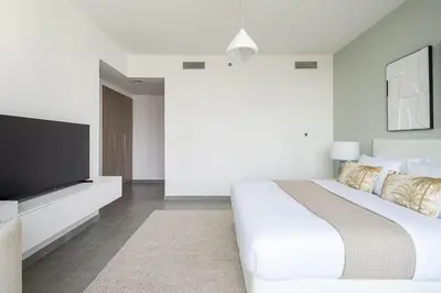 a white bedroom with a large bed and a flat screen tv at Frank Porter - Stella Maris in Dubai