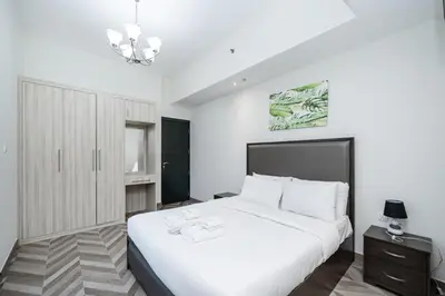 a white bedroom with a large bed and a chandelier at Stylish 4BR with Jacuzzi, Sauna & Prime Amenities in Dubai