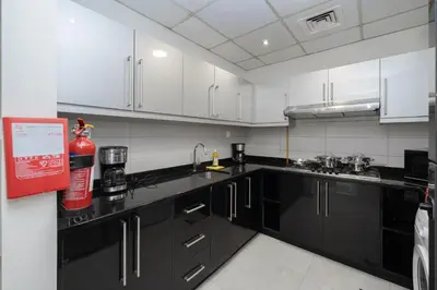 a kitchen with black counters and white cabinets at Stylish 4BR with Jacuzzi, Sauna & Prime Amenities in Dubai