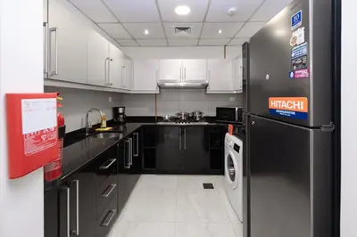a kitchen with black and white cabinets and a refrigerator at Stylish 4BR with Jacuzzi, Sauna & Prime Amenities in Dubai