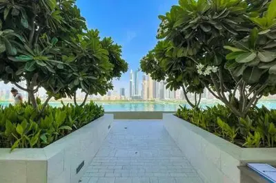a walkway with trees and a view of a city at Private Beachfront 1 Bed With 180 view of Marina Skyline in Dubai