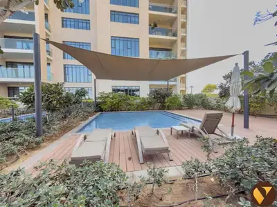 a swimming pool with a hammock and chairs next to a building at Vogue Emirates Hills, Vida The Hills Residence near Marina and JBR, One Bedroom Apartment with Balcony, Golf Club and City Skyline View, Access to all Amenities in Dubai