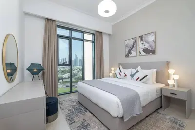 a white bedroom with a large bed and a window at Vogue Emirates Hills, Vida The Hills Residence near Marina and JBR, One Bedroom Apartment with Balcony, Golf Club and City Skyline View, Access to all Amenities in Dubai