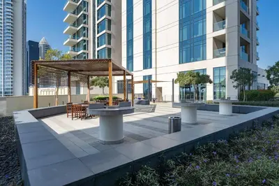 a pavilion with a table and chairs in front of a building at Vogue Emirates Hills, Vida The Hills Residence near Marina and JBR, One Bedroom Apartment with Balcony, Golf Club and City Skyline View, Access to all Amenities in Dubai