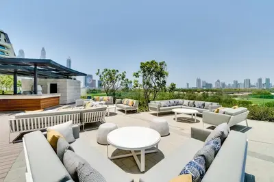 a patio with white couches and a table and chairs at Vogue Emirates Hills, Vida The Hills Residence near Marina and JBR, One Bedroom Apartment with Balcony, Golf Club and City Skyline View, Access to all Amenities in Dubai