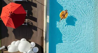 a person jumping into a pool with a red umbrella at Elegant Palm Jumeirah Retreat with Breathtaking Sea Views By AYA Boutique in Dubai