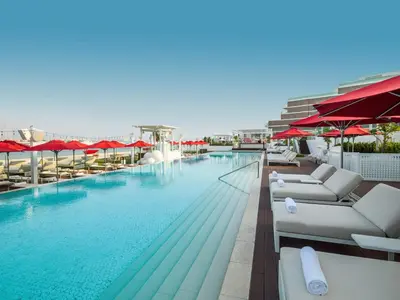 a large swimming pool with lounge chairs and umbrellas at Elegant Palm Jumeirah Retreat with Breathtaking Sea Views By AYA Boutique in Dubai