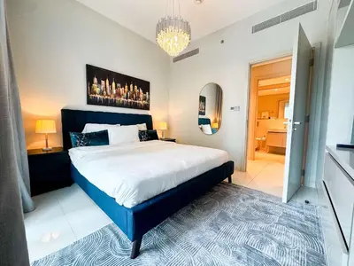 a bedroom with a large bed and a chandelier at Glamorous 3BR with Marina view in Dubai