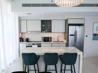a kitchen with a white counter with chairs and a refrigerator at Glamorous 3BR with Marina view in Dubai