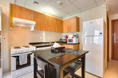a kitchen with wooden cabinets and a white refrigerator at Beautiful Studio on 10 floor of Marina View Tower in Dubai