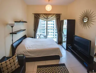 a bedroom with a bed and a tv and a balcony at Beautiful Studio on 10 floor of Marina View Tower in Dubai