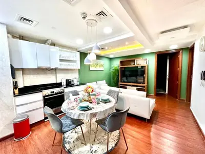 a kitchen and a living room with a table and chairs at Cozy Apartment In Laya Residence JVC in Dubai