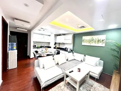 a living room with white furniture and a green wall at Cozy Apartment In Laya Residence JVC in Dubai