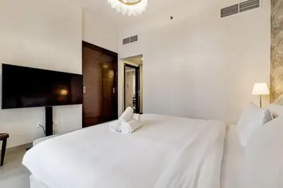a white bedroom with a large white bed and a chandelier at Vacationer I Sparkle T1 2 Bedroom I Marina Views I Steps away from Beach I Gym, Pool, Parking & Wi-Fi in Dubai