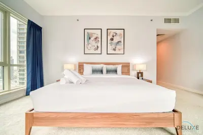 a bedroom with a large white bed with blue curtains at Alluring 2BR at Al Majara 1 Dubai Marina by Deluxe Holiday Homes in Dubai