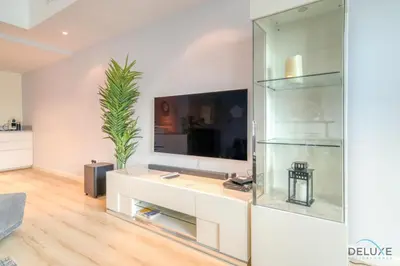 a living room with a tv and a glass wall at Alluring 2BR at Al Majara 1 Dubai Marina by Deluxe Holiday Homes in Dubai