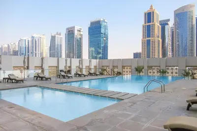 a pool on the roof of a building with tall buildings at Frank Porter - West Avenue in Dubai