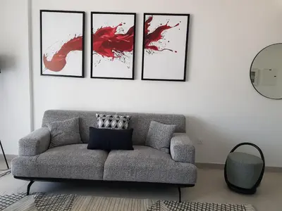 a living room with a couch and four pictures on the wall at Stylish 1 Bedroom Apartment Near Burj Al Arab (Madinat Jumeirah) in Dubai
