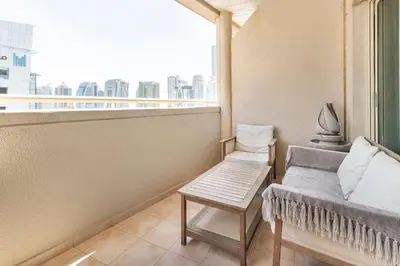 a balcony with a couch and a chair and a window at Holiday Home near beach & metro in Dubai