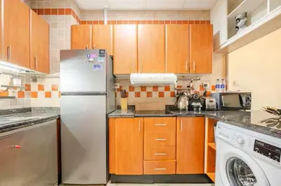 a kitchen with wooden cabinets and a white refrigerator at Holiday Home near beach & metro in Dubai