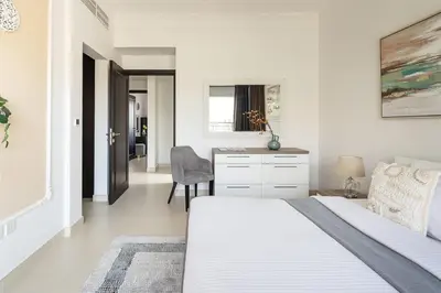 a white bedroom with a bed and a desk at Frank Porter - Serena Casa Viva in Dubai