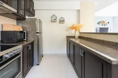 a kitchen with black cabinets and a stainless steel refrigerator at Frank Porter - Serena Casa Viva in Dubai