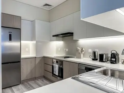 a kitchen with white cabinets and stainless steel appliances at Fantastic flat in TiaraResidence in Dubai