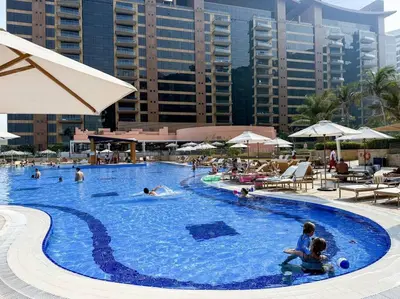 a large swimming pool with people in a resort at Fantastic flat in TiaraResidence in Dubai