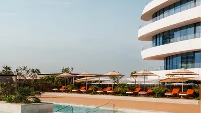 a pool with chairs and umbrellas next to a building at Jumeirah Residences Marsa Al Arab Dubai in Dubai