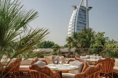 a restaurant with tables and chairs and a tall building at Jumeirah Marsa Al Arab Dubai in Dubai