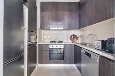 a kitchen with wooden cabinets and stainless steel appliances at GuestReady - Modern home with stunning city views in Dubai