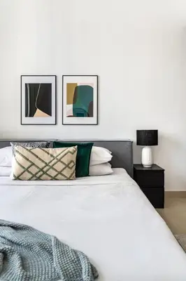 a bedroom with a white bed with three pictures on the wall at GuestReady - Modern home with stunning city views in Dubai