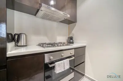a small kitchen with a stove and a microwave at Graceful 1BR at Merano Business Bay by Deluxe Holiday Homes in Dubai
