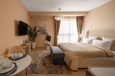 a bedroom with a bed and a table and a window at Happy ACADEMIA JBR in Dubai
