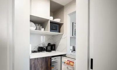 a kitchen with white walls and white shelves at Happy ACADEMIA JBR in Dubai