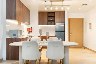 a kitchen with a white table and chairs at Stylish 1BR Apartment in La Mer Dubai with Balcony and Partial Marina Views in Dubai