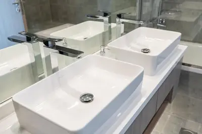 a bathroom with two white sinks and a mirror at Urban tropic 3 bedroom apartment with full sea view by Suiteable Interiors in Dubai