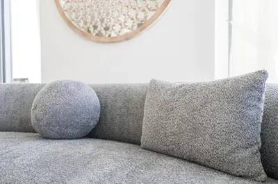 a couch with two pillows and a mirror on the wall at Urban tropic 3 bedroom apartment with full sea view by Suiteable Interiors in Dubai