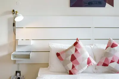 a bedroom with a white bed with red and white pillows at Bright & Vibrant 2BR+kids room 7min to Dubai Mall in Dubai