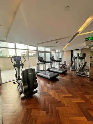 a gym with several treadmills and machines in a room at Majestine Apartments in Dubai