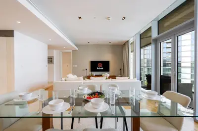 a dining room with a glass table and white chairs at High-End 1BR Bluewaters Luxury Near Ain Dubai in Dubai