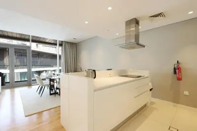 a kitchen with white cabinets and a dining room at High-End 1BR Bluewaters Luxury Near Ain Dubai in Dubai
