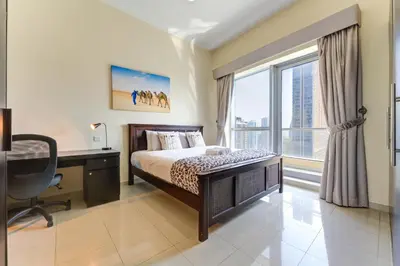 a bedroom with a bed and a desk and a window at Bay Central, Dubai Marina - Peaceful One Bedroom in Dubai