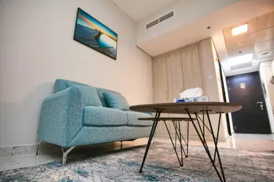 a living room with a blue couch and a table at Exceptional Furnished Studio in Dubai