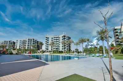 a large swimming pool with palm trees and buildings at Exceptional Furnished Studio in Dubai