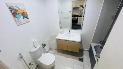 a white bathroom with a toilet and a sink at Newly Furnished bright and cozy studio apartment - Damac Hills in Dubai