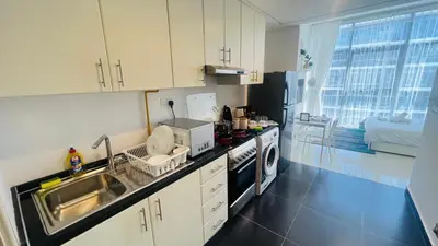 a kitchen with a sink and a stove top oven at Newly Furnished bright and cozy studio apartment - Damac Hills in Dubai