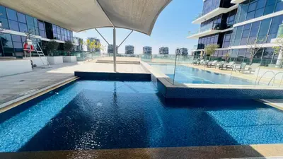 a swimming pool in the middle of a building at Newly Furnished bright and cozy studio apartment - Damac Hills in Dubai